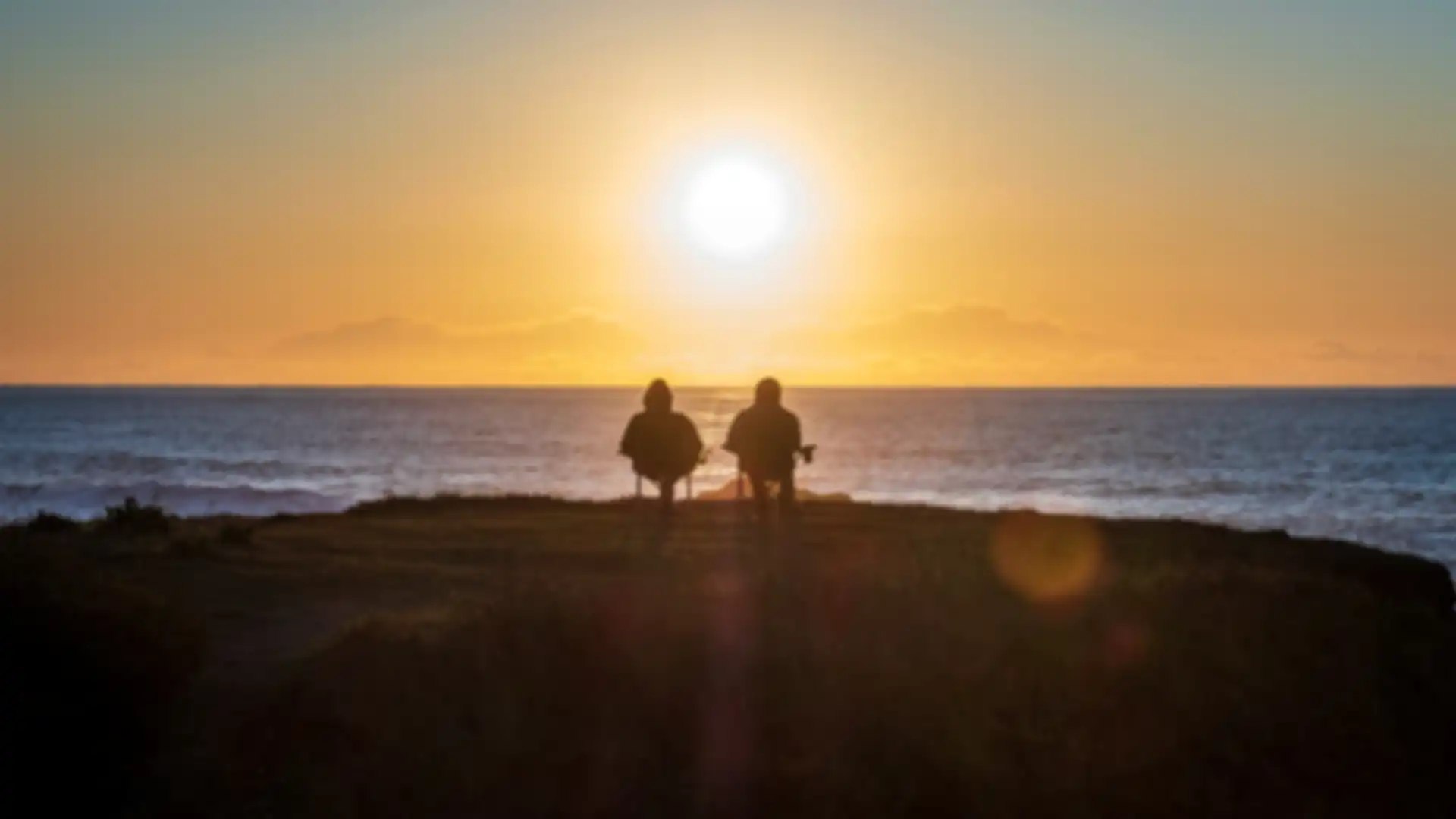 Two people sitting outside at sunset