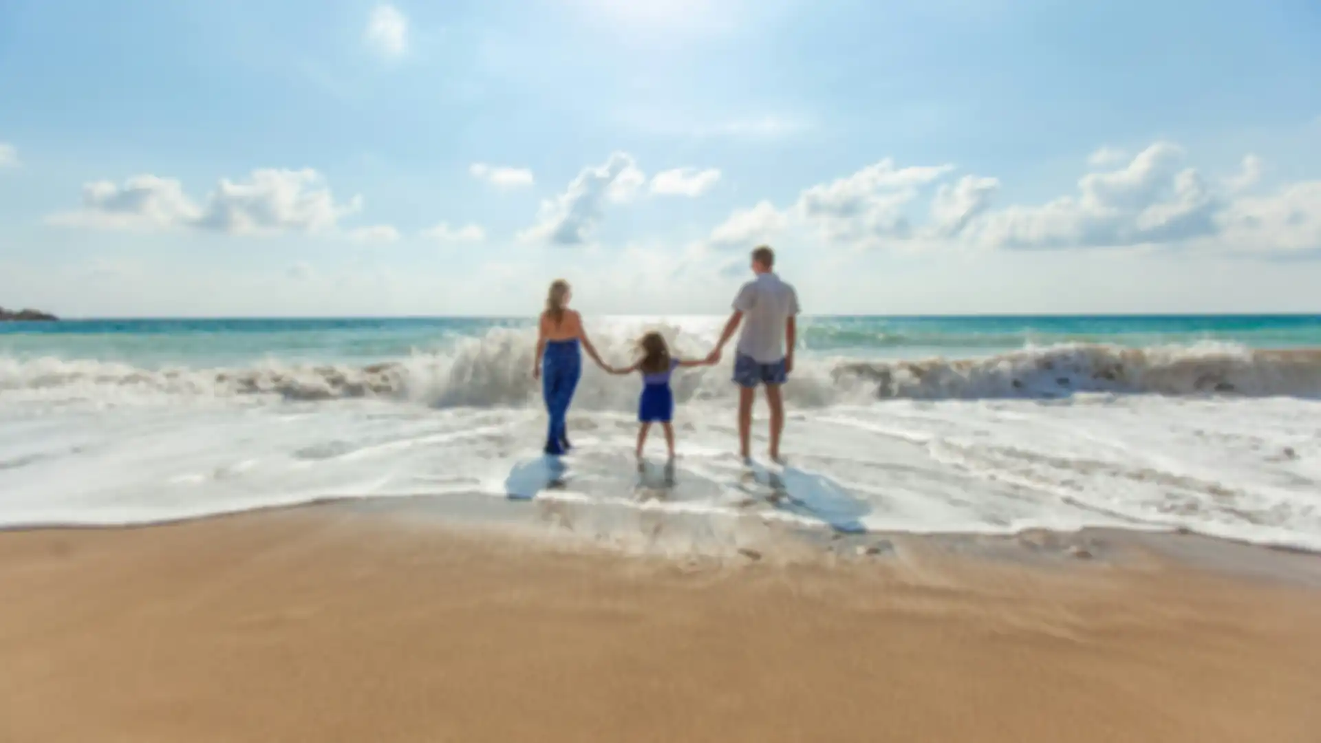 Parents and child standing in the tide at a beach